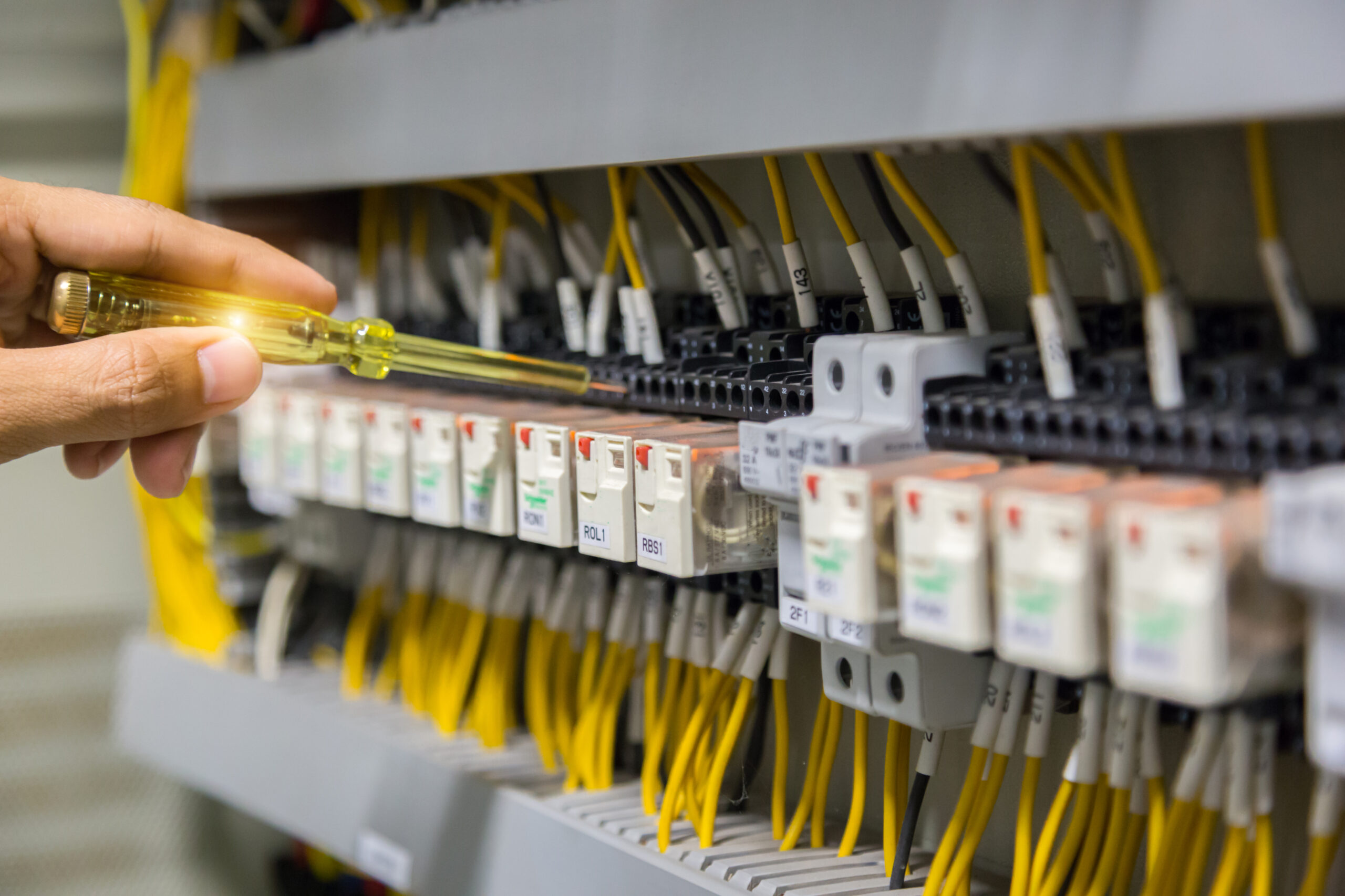 Electricians hands testing current electric in control panel.
